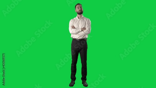 Satisfied business man watching with crossed arms approving with head nodding. Full length on green screen chroma key background