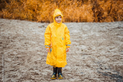 Boy in yellow raincoat on a deserted beach on a cloudy day