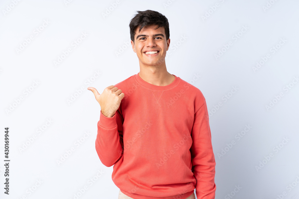 Handsome man over isolated blue background pointing to the side to present a product Handsome man over isolated blue background pointing to the side to present a product
