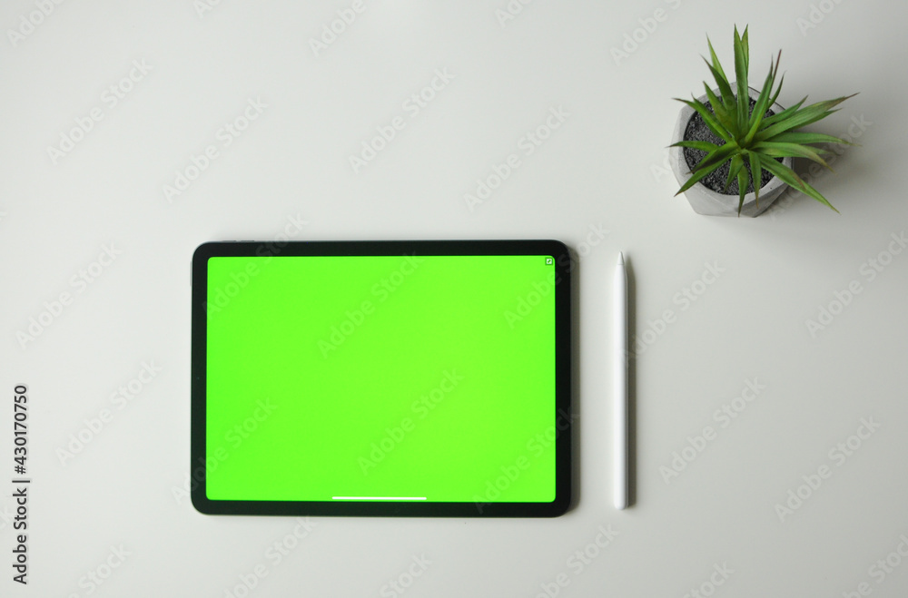 Green background mock-up on tablet device with stylus. Minimalism style top view Green background mock-up on tablet device with stylus. Minimalism style top view