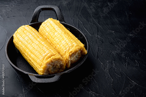 Homemade golden sweet corn cob, on black stone background, with copy space for text