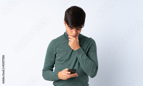 Handsome man over isolated blue background thinking and sending a message