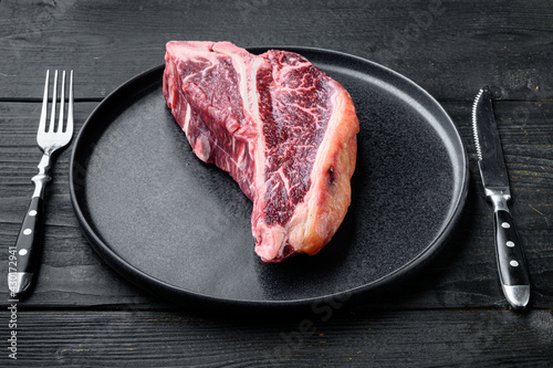 Italian Florentine T bone dry aged beef meat Steak, on plate, on black wooden table background