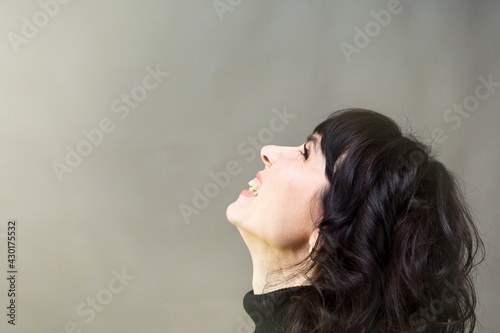 Brunette woman in profile on a gray background. Short black hair