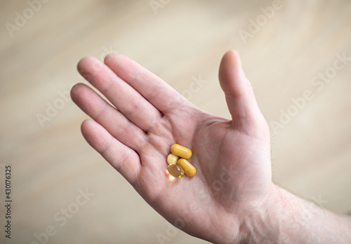 Vitamins and supplements. The man is holding the tablets in his right hand. Pills in hand representing health, help and medicine concept