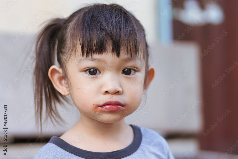 Portrait image of 3-4 years old of kid. Sloppy face and mouth of Happy Asian child girl when she eating and biting an ice cream.