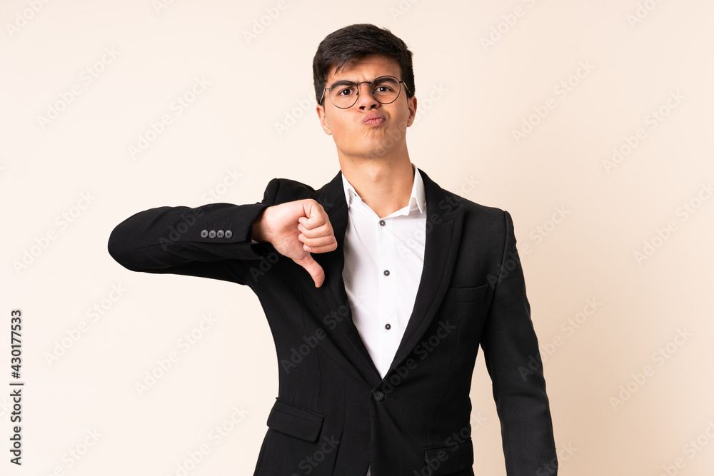 Naklejka premium Businessman over isolated beige background showing thumb down sign