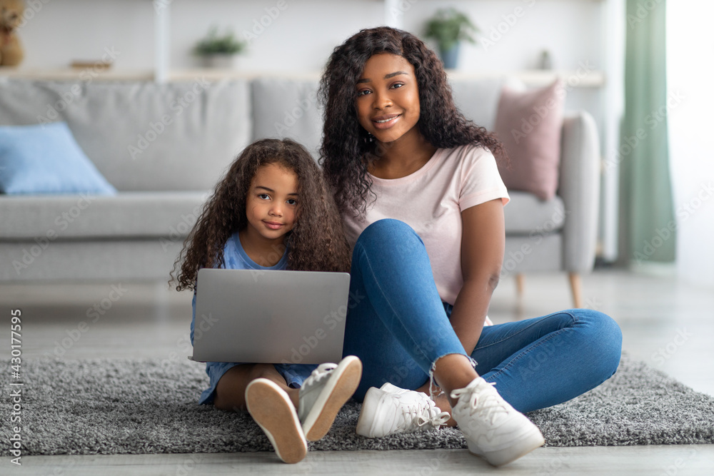 Distance education concept. Happy black mom and her cute little daughter watching online lesson on laptop at home Distance education concept. Happy black mom and her cute little daughter watching online lesson on laptop at home