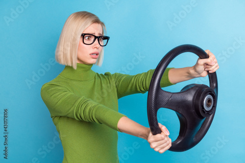 Photo of unhappy upset afraid scared woman in glasses riding car hold steering wheel isolated on blue color background