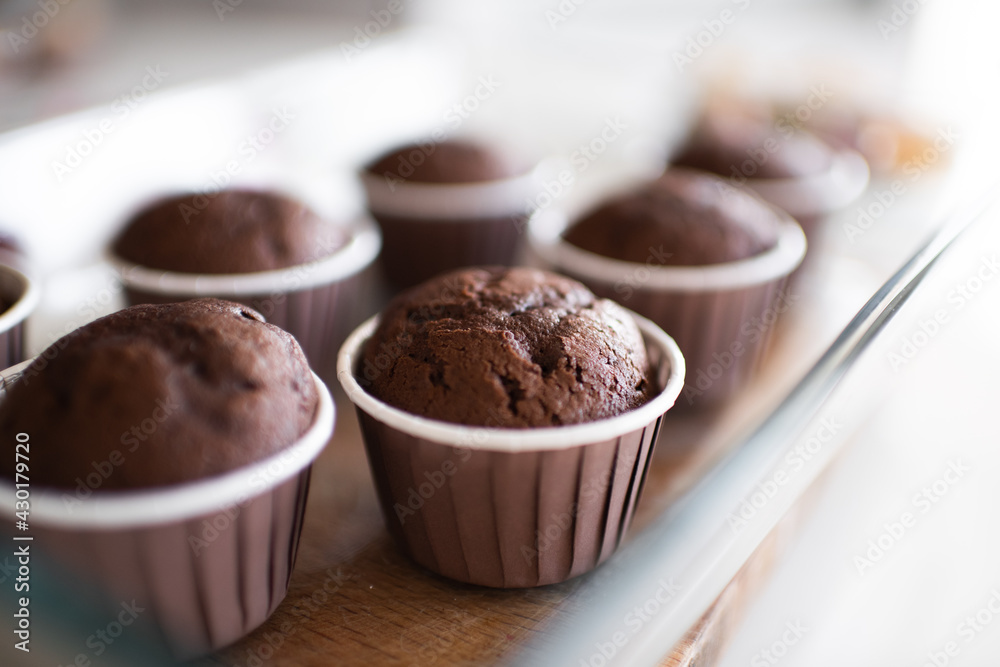 Fresh baked chocolate muffins in forms at kitchen table close up. Healthy eating. Cooking at home. Fresh baked chocolate muffins in forms at kitchen table close up. Healthy eating. Cooking at home.
