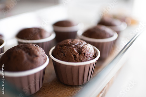 Fresh baked chocolate muffins in forms at kitchen table close up. Healthy eating. Cooking at home.