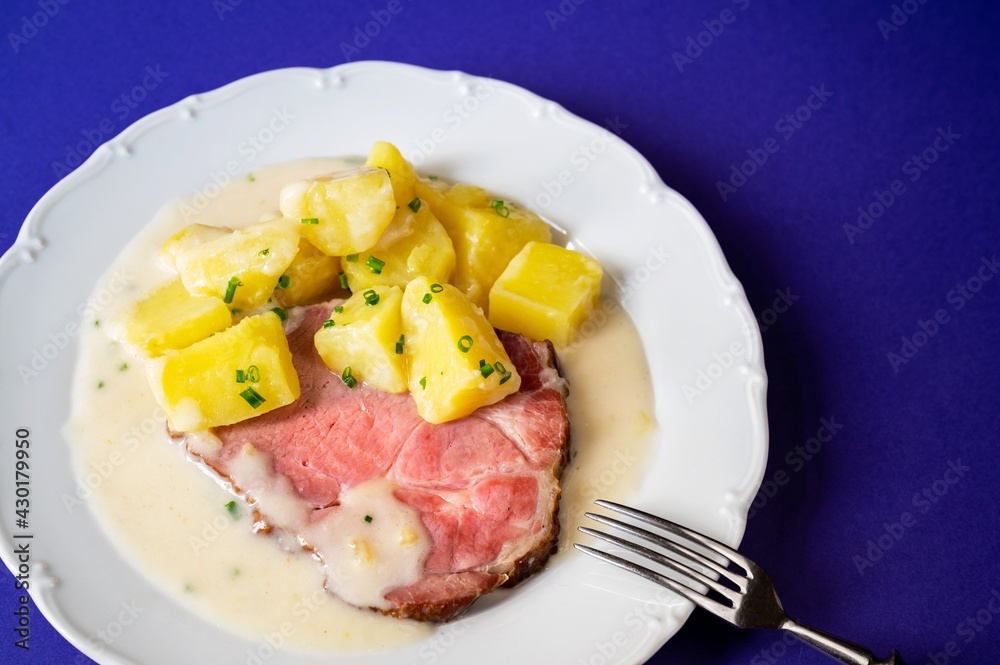Smoked meat fillet, boiled potato and spicy horseradish sauce on white plate on blue. Smoked meat fillet, boiled potato and spicy horseradish sauce on white plate on blue.