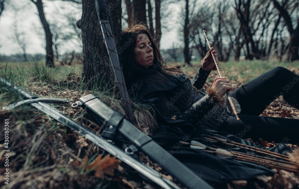 Woman in image of medieval warrior lies and rests in forest. Woman in image of medieval warrior lies and rests in forest.