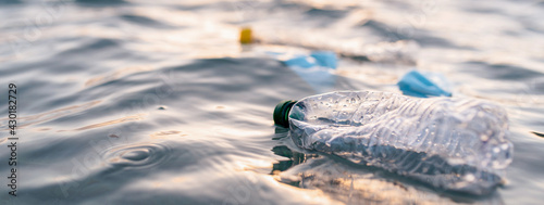 Horizontal banner or header Garbage floating on sea or ocean water with plastic bottles and face masks. Pollution and environmental damage concept. © Pintau Studio