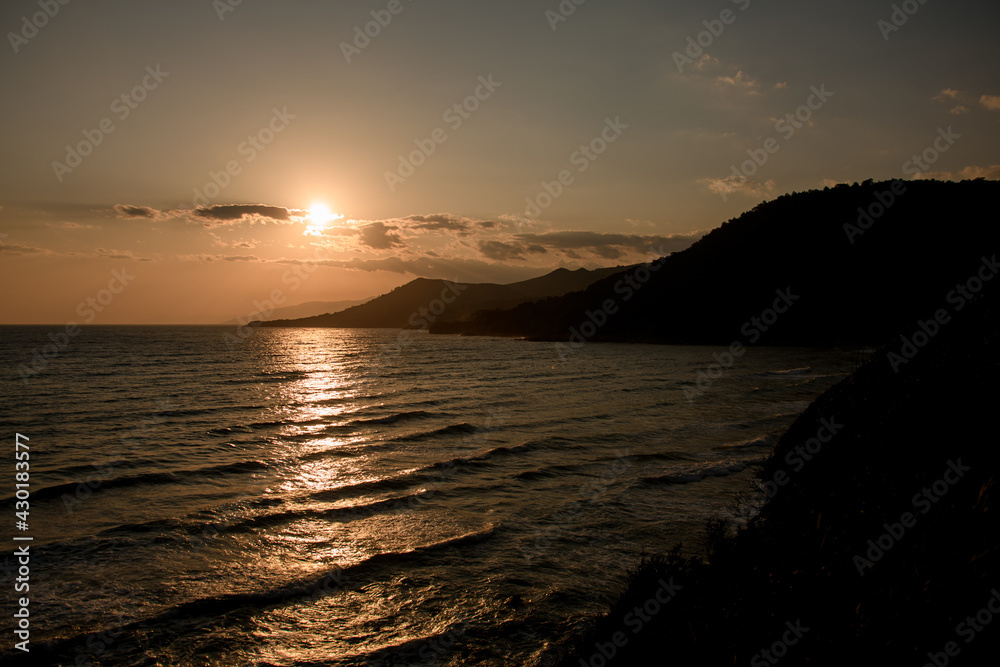 Wonderful hill landscape with view of mountains and ocean and sunny sunset