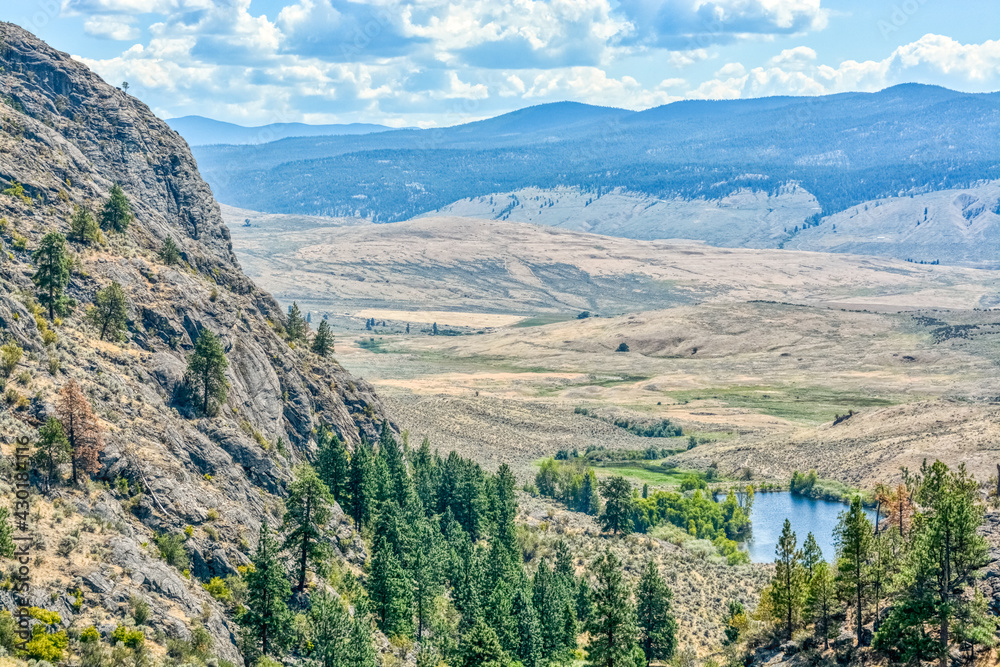 Scenery view of a valley with small lake downhill on a bright sunny day