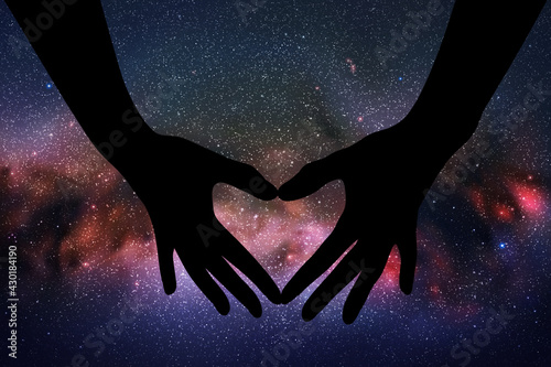 Heart shaped hands. Hand gesture silhouette. Starry sky and Milky Way