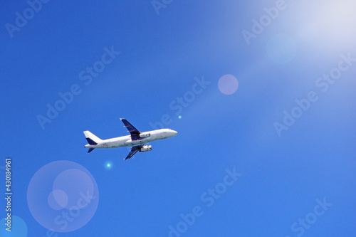 Plane flying high in blue sky with sunny rays