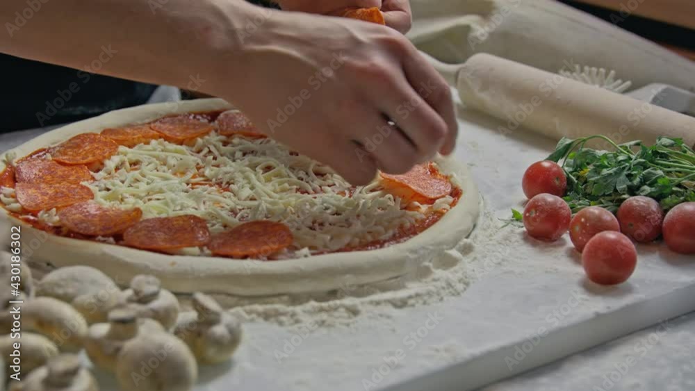 Professional baker prepares traditional Italian pizza. Cooking pizza in restaurant in kitchen. cook puts pieces of cheese on dough. process of making pizza in a pizzeria Professional baker prepares traditional Italian pizza. Cooking pizza in restaurant in kitchen. cook puts pieces of cheese on dough. process of making pizza in a pizzeria
