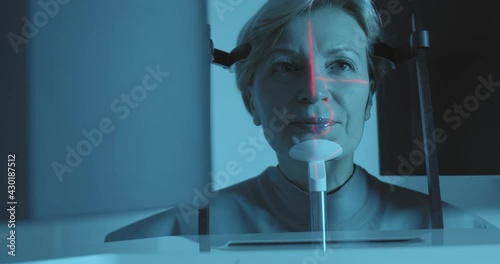 Close-up a female patient that is putting down her head to the white detail for the panoramic scanning inside of the 3D dental cone beam computerized tomography.