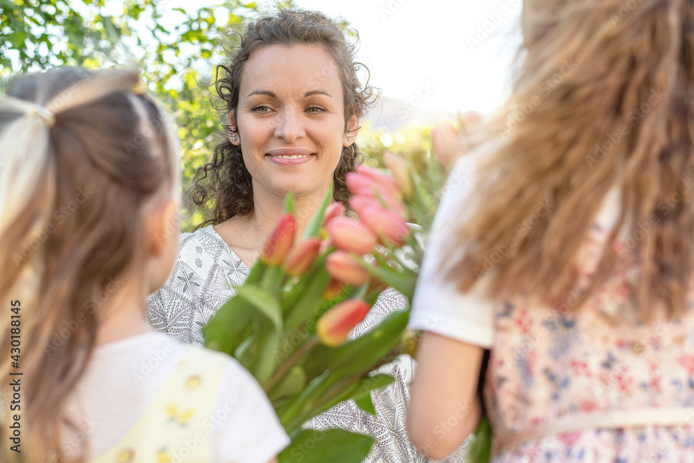 Happy mother's day. Little cute girls holding flowers as a gift for her mother. Summer garden background. Mother's day or birthday concept. Happy mother's day. Little cute girls holding flowers as a gift for her mother. Summer garden background. Mother's day or birthday concept.