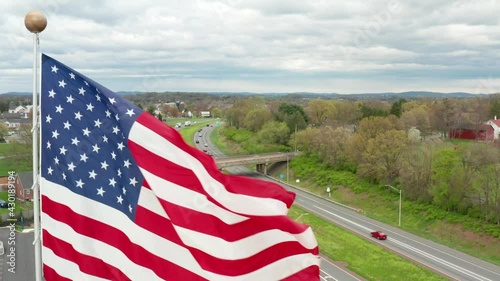 Close-up aerial of America flag waving in breeze. Features beauty and pride in USA. Travel transportation theme. Highway infrastructure theme.