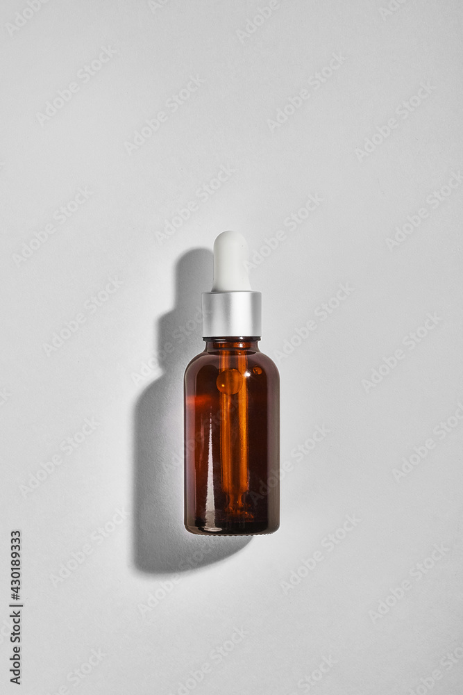 Amber dropper glass bottle on grey background. Mockup