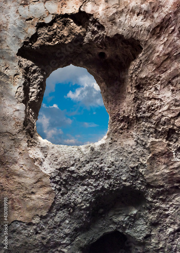 Hole in the wall overlooking the peaceful sky after the war. Stone frame in an old house.