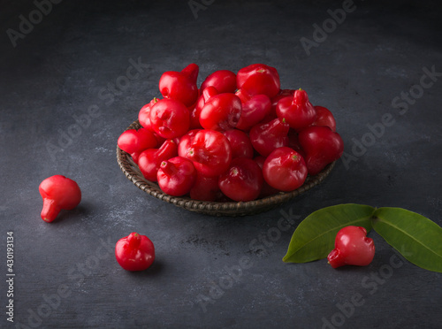 jambu or rose apple, bell-like shape fruit also called bell fruit or wax apple, sri lanka juicy fruits in a basket, taken on dark background photo