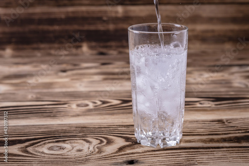 fresh seltzer water is poured into a glass with ice.