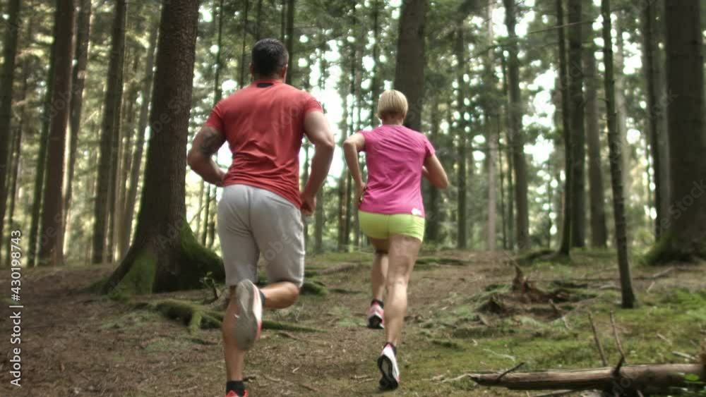 Caucasian couple running in the forest, at the end of the run giving high five to each other Caucasian couple running in the forest, at the end of the run giving high five to each other