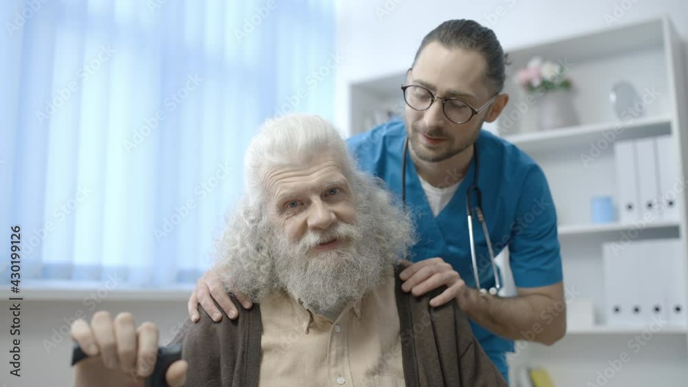 Smiling clinic worker and senior man looking at camera, medical care for elderly