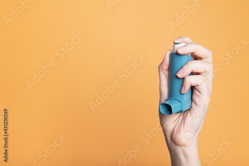 Hand holds inhaler to treat asthma. World Asthma Day. Concept of allergy care. Copy space photo