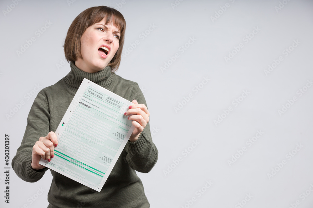 woman holding an empty tax declaration form and makes a wry face woman holding an empty tax declaration form and makes a wry face