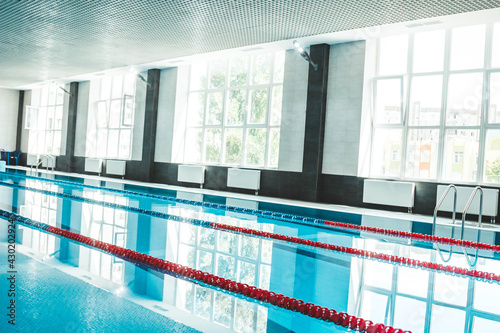 a water pool with blue transparent clear water, on which bright sunlight shines. Water lanes in the swimming pool. indoor sports field for swimming