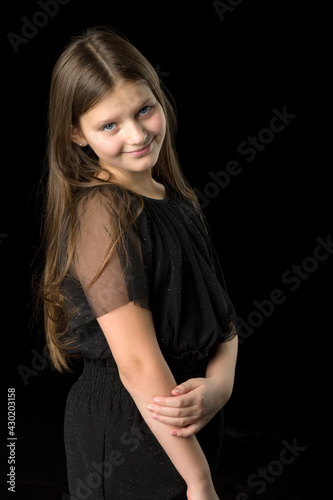Close up view of a cute smiling little girl posing on black background.