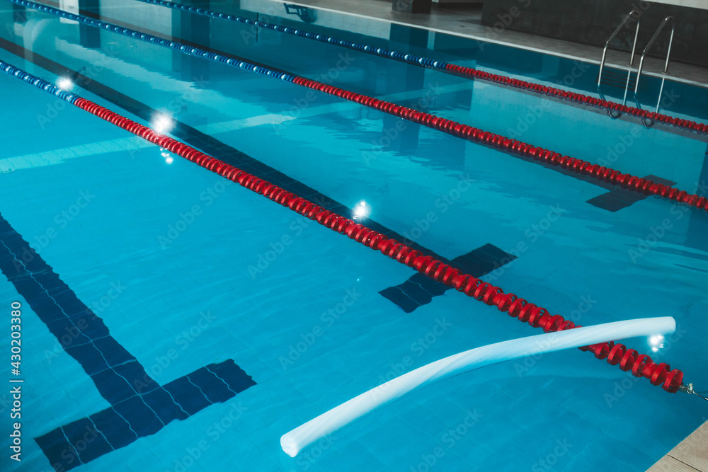 a water pool with blue transparent clear water, on which bright sunlight shines. Water lanes in the swimming pool. indoor sports field for swimming