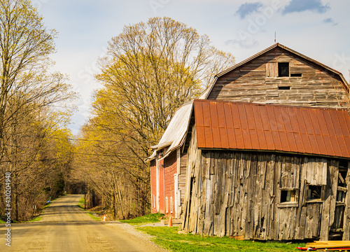 Φωτογραφία old battered wooden barn on a country dirt road