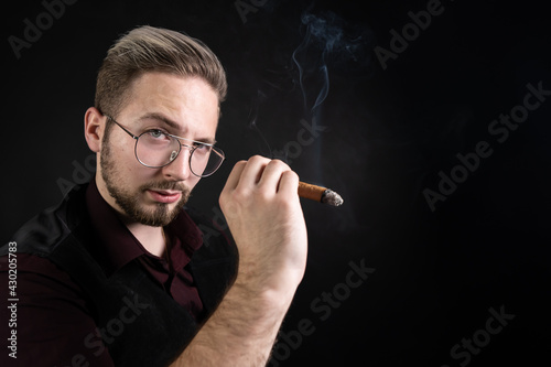 Young handsome man smokes a cigar.