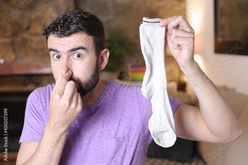 Disgusted man holding stinky sock