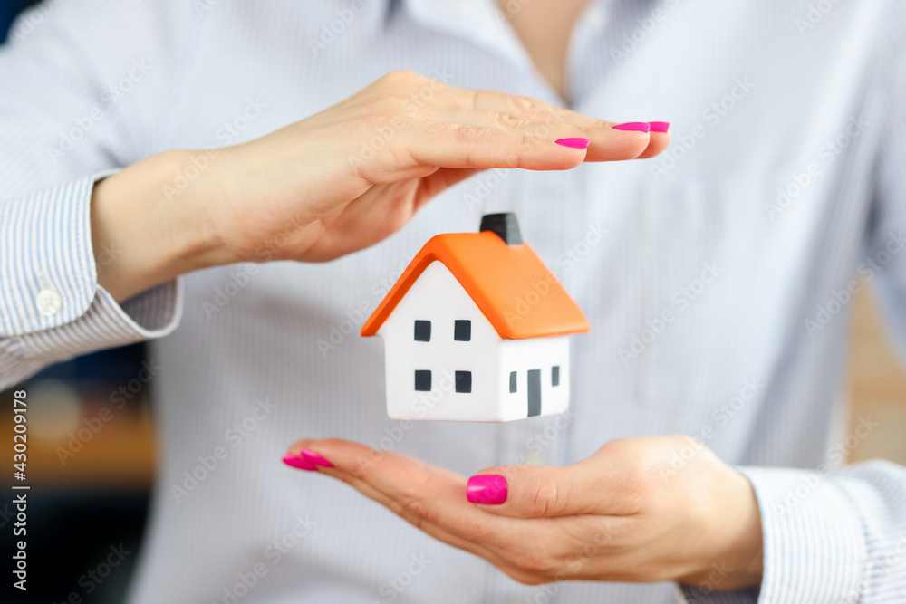Small house inside female hands. Home insurance against natural disasters Small house inside female hands. Home insurance against natural disasters