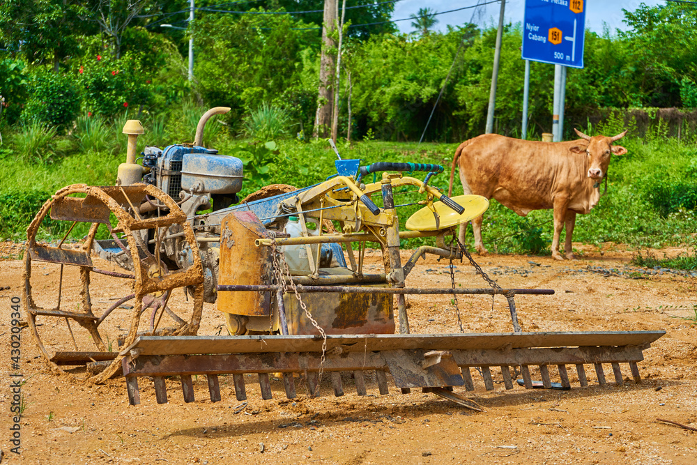 Obraz premium A strange homemade tool for plowing a field from a rebuilt motorbike. Agricultural village in Asia