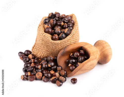 Guarana seed in bag and wooden scoop, isolated on white background. Dietary supplement guarana, caffeine cource for energy drinks. photo