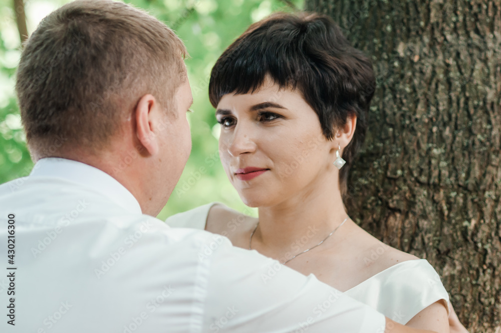 Newlyweds hug and kiss on the background of the forest. A man hugs and kisses a woman Newlyweds hug and kiss on the background of the forest. A man hugs and kisses a woman