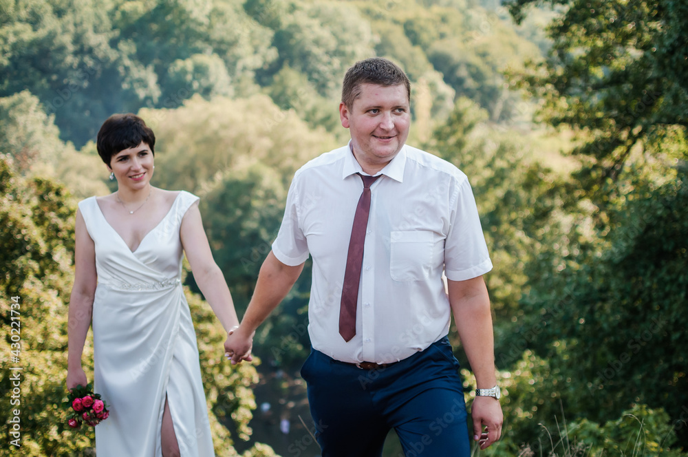 Newlyweds hold hands on the background of the forest Newlyweds hold hands on the background of the forest