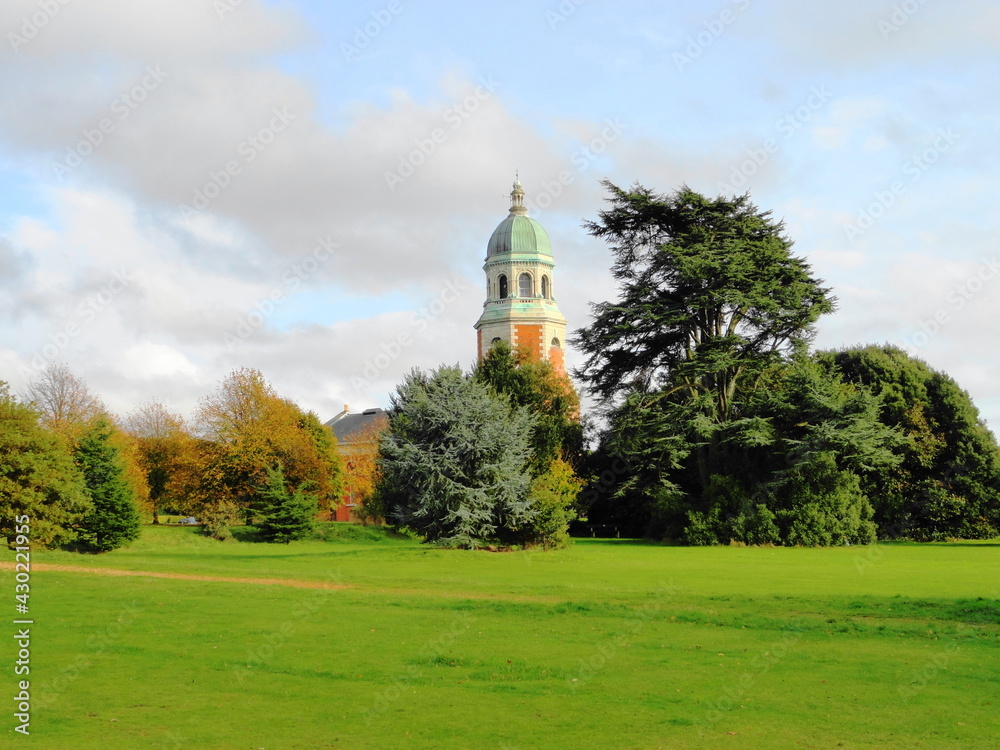 Old tower of church building viewed from behind trees and field Old tower of church building viewed from behind trees and field