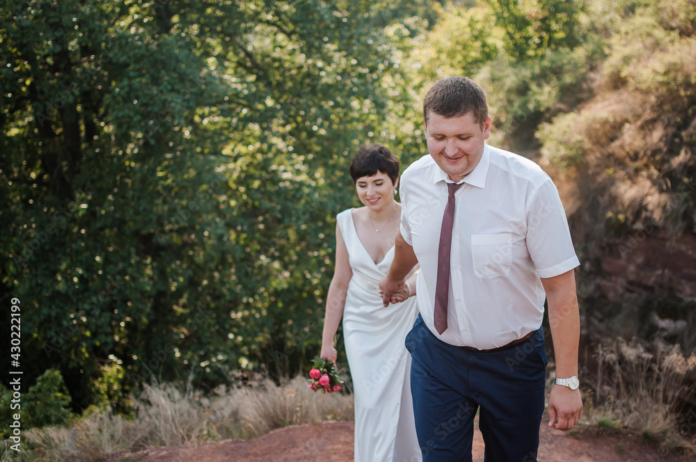Obraz premium Newlyweds hold hands on the background of the forest