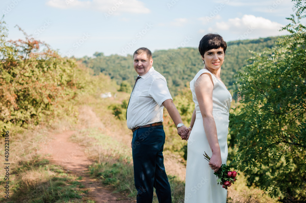 Newlyweds hold hands on the background of the forest Newlyweds hold hands on the background of the forest