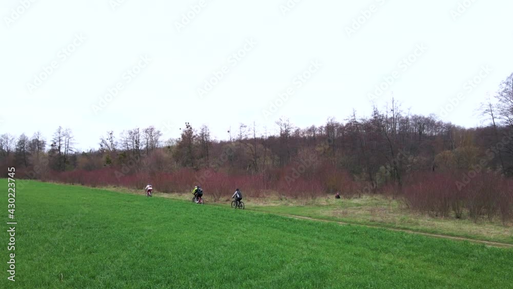 Aerial shot of young sport men ride bicycles on countryside road near green field at spring cloudy day. Healthy cycling lifestyle Aerial shot of young sport men ride bicycles on countryside road near green field at spring cloudy day. Healthy cycling lifestyle