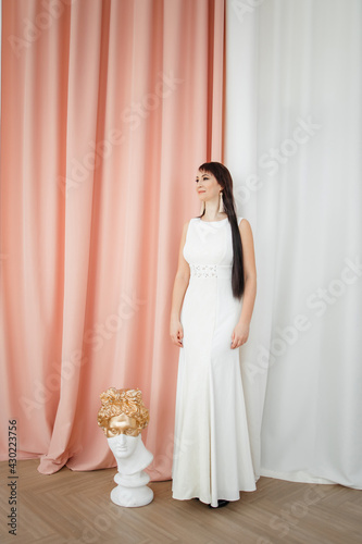 caucasian brunette girl with long hair in a white long dress. the concept of beauty.